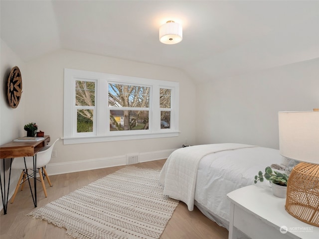 bedroom with light wood-type flooring and vaulted ceiling