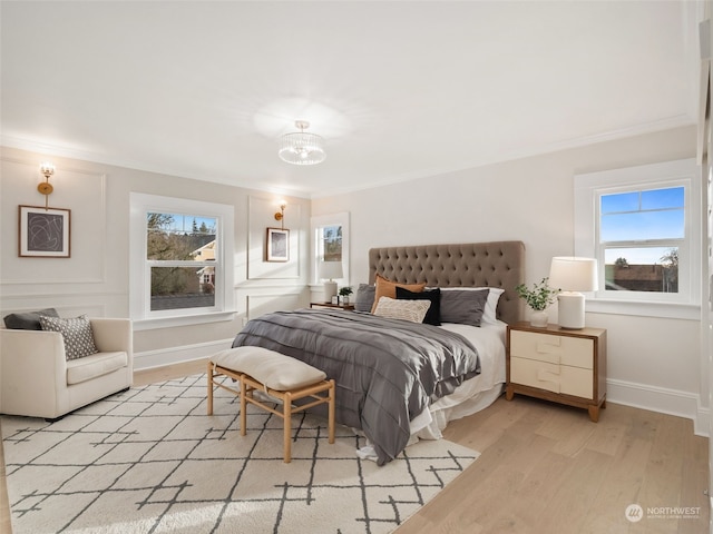 bedroom featuring a chandelier, light hardwood / wood-style floors, and crown molding