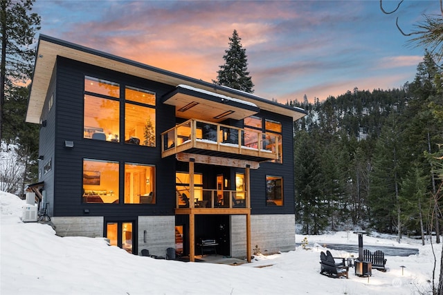 snow covered back of property with a balcony