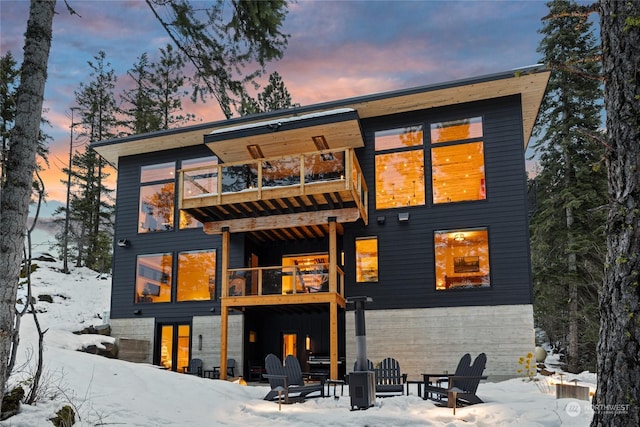 snow covered house featuring a balcony