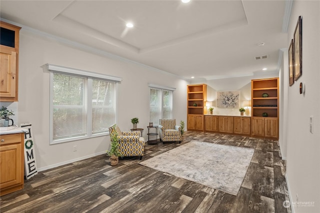 sitting room with a raised ceiling, crown molding, and dark wood-type flooring