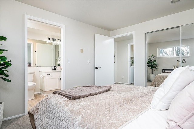 bedroom featuring light carpet, ensuite bath, and a closet