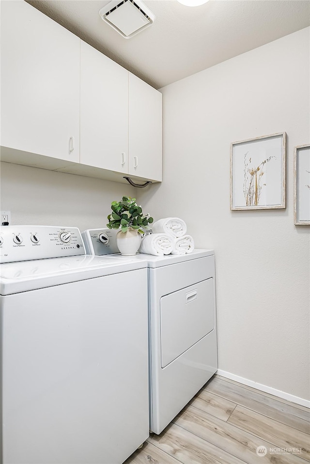 laundry area featuring cabinets, washing machine and clothes dryer, and light wood-type flooring