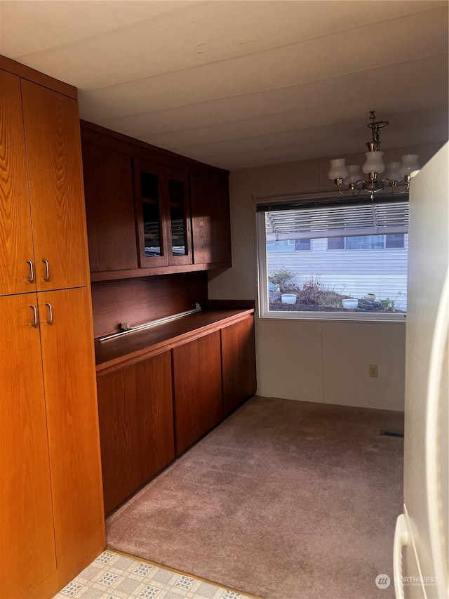 kitchen featuring light carpet, white fridge, and an inviting chandelier