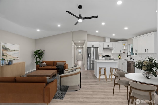 living room with light wood-type flooring, vaulted ceiling, a ceiling fan, and recessed lighting