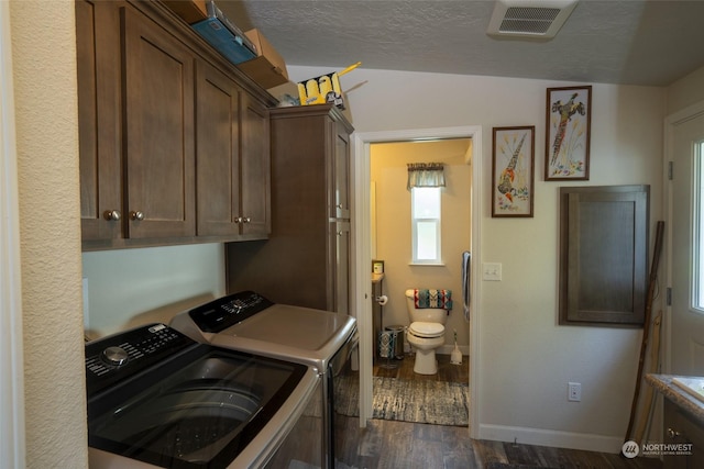 clothes washing area featuring cabinets, a textured ceiling, separate washer and dryer, and dark hardwood / wood-style floors