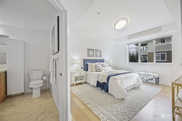 bedroom featuring a tray ceiling and light wood-type flooring