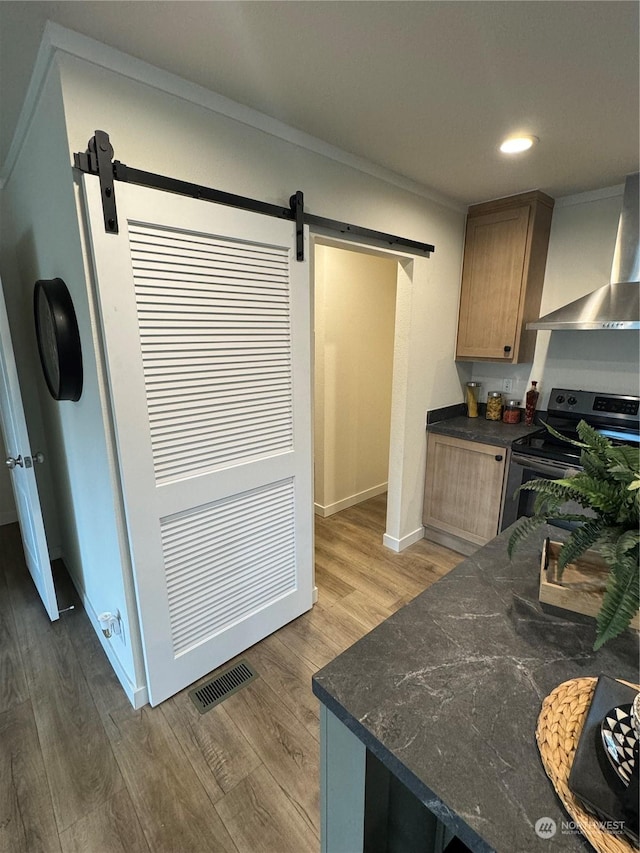 kitchen with stainless steel range with electric cooktop, wall chimney range hood, crown molding, dark hardwood / wood-style floors, and a barn door