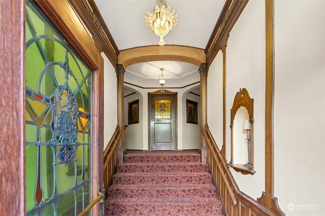 stairway featuring crown molding, carpet floors, and an inviting chandelier