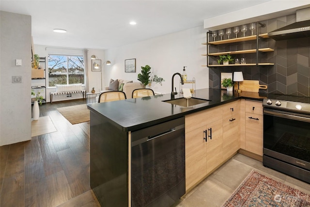 kitchen with sink, stainless steel appliances, wall chimney range hood, kitchen peninsula, and light brown cabinetry