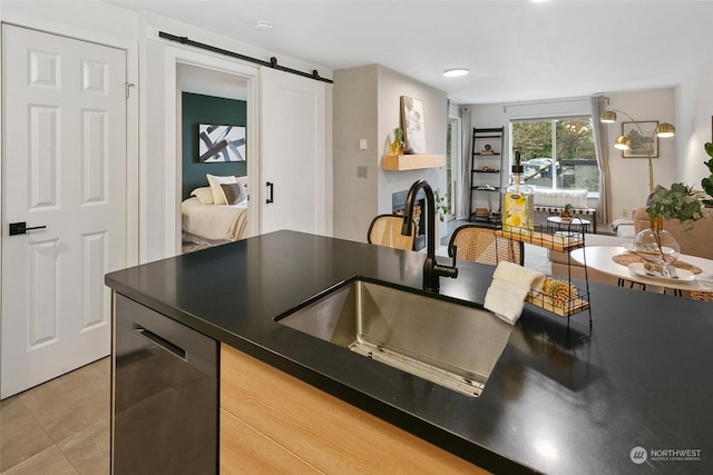 kitchen featuring a barn door, dishwasher, tile patterned flooring, and sink