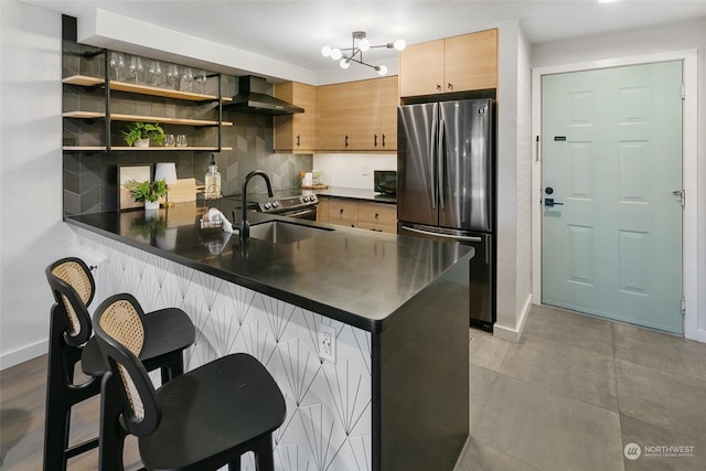 kitchen with wall chimney range hood, sink, appliances with stainless steel finishes, tasteful backsplash, and kitchen peninsula