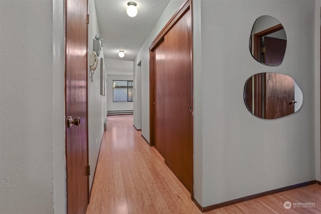 hallway with baseboard heating, a textured ceiling, and light hardwood / wood-style flooring