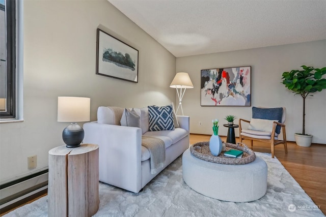 living room featuring hardwood / wood-style flooring, baseboard heating, and a textured ceiling