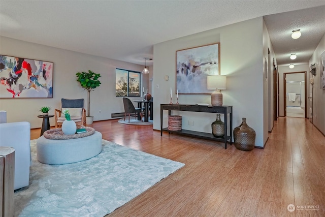 living room with hardwood / wood-style flooring, baseboard heating, and a textured ceiling