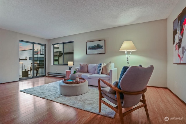 living room featuring light hardwood / wood-style floors, a textured ceiling, and a baseboard heating unit