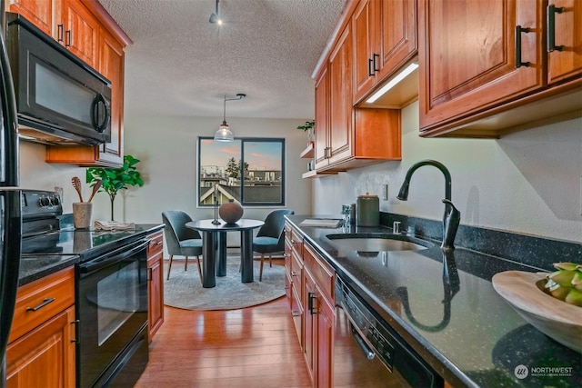 kitchen with black appliances, sink, a textured ceiling, decorative light fixtures, and wood-type flooring