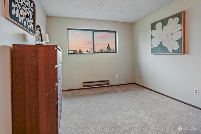 carpeted empty room featuring baseboard heating and a textured ceiling