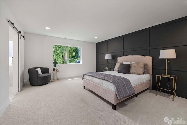 bedroom with a barn door and light colored carpet