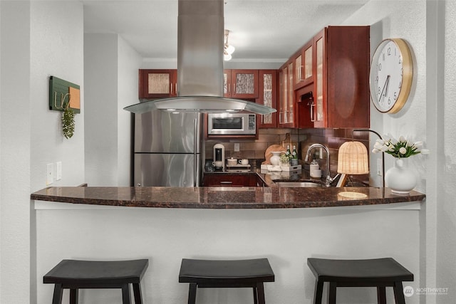 kitchen featuring island range hood, stainless steel appliances, sink, and a breakfast bar area