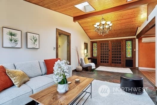 living room with lofted ceiling with beams, a wall unit AC, an inviting chandelier, and wooden ceiling