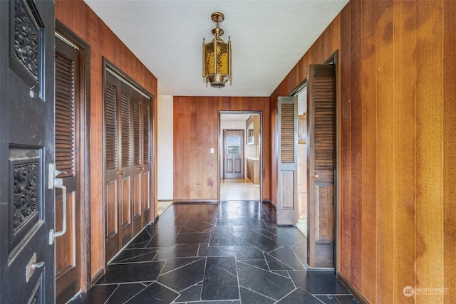 hallway featuring a textured ceiling and wood walls