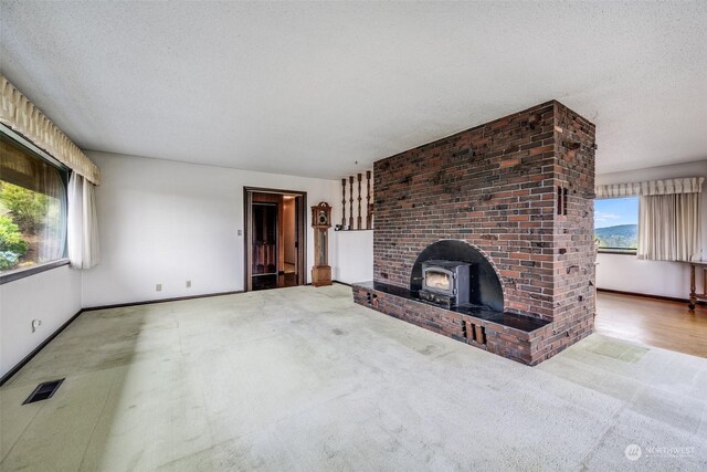 unfurnished living room with carpet, a wood stove, and a textured ceiling