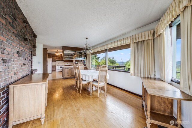 dining room featuring light hardwood / wood-style floors, a chandelier, and a textured ceiling