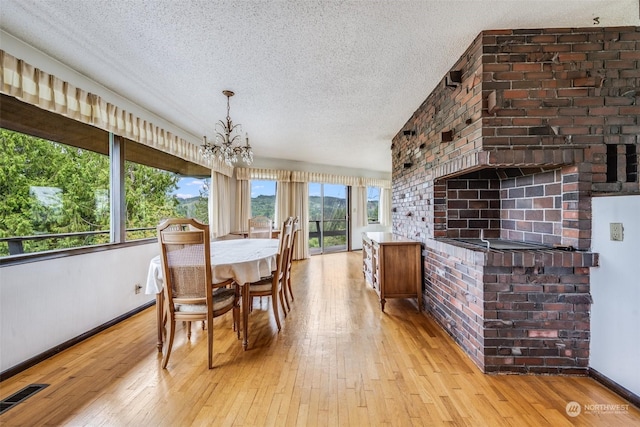 dining space featuring light hardwood / wood-style floors, a chandelier, and a textured ceiling