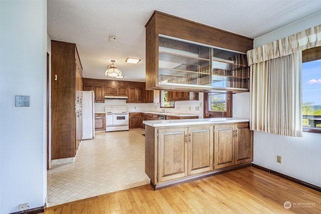 kitchen featuring white appliances, kitchen peninsula, light hardwood / wood-style floors, and a textured ceiling