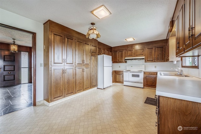 kitchen with sink, pendant lighting, a textured ceiling, and white appliances