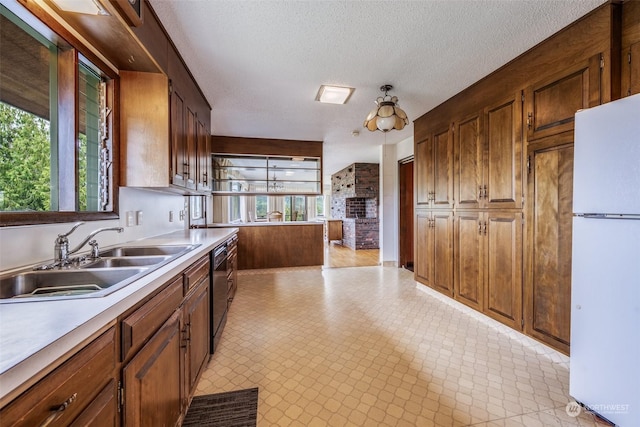 kitchen featuring black dishwasher, white fridge, sink, and a textured ceiling