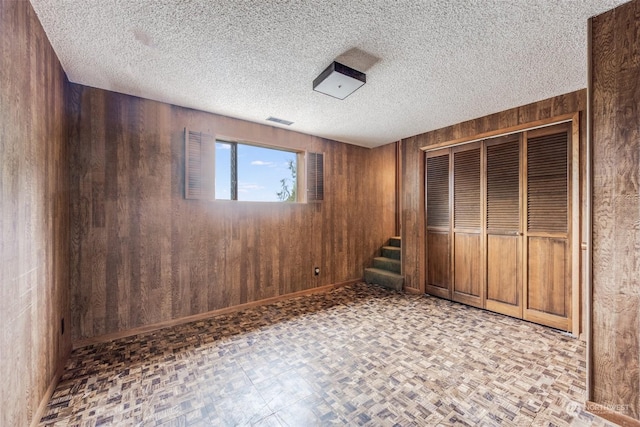 unfurnished bedroom featuring a closet, a textured ceiling, and wood walls