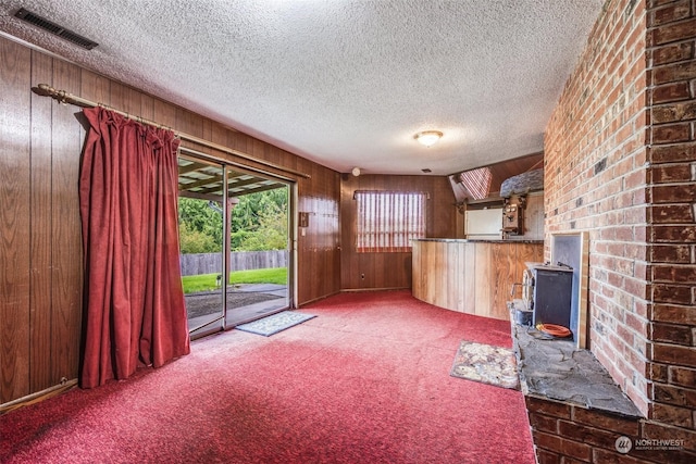 unfurnished living room featuring wooden walls, carpet floors, and a textured ceiling