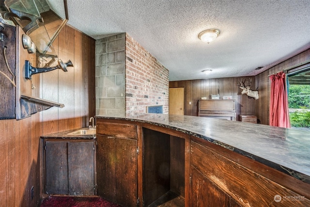 bar featuring sink, wooden walls, and a textured ceiling