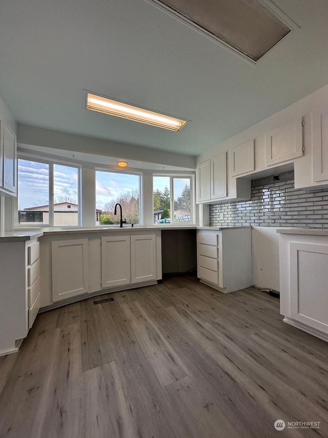 kitchen with backsplash, sink, white cabinets, and light hardwood / wood-style floors