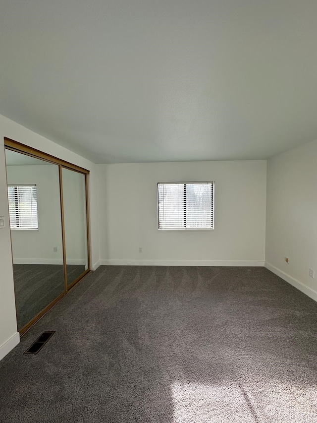 unfurnished bedroom with dark colored carpet and a closet