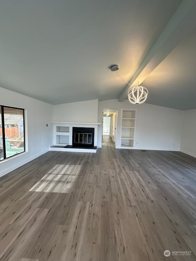 unfurnished living room featuring built in shelves, wood-type flooring, and a notable chandelier