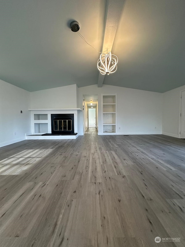 unfurnished living room with built in shelves, hardwood / wood-style flooring, lofted ceiling, and a notable chandelier