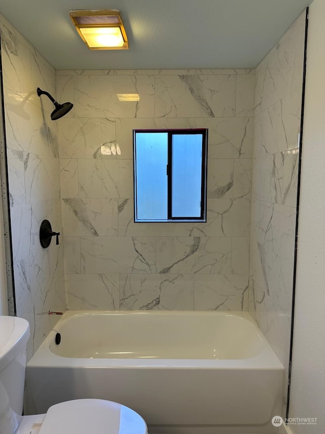 bathroom with tiled shower / bath combo and toilet