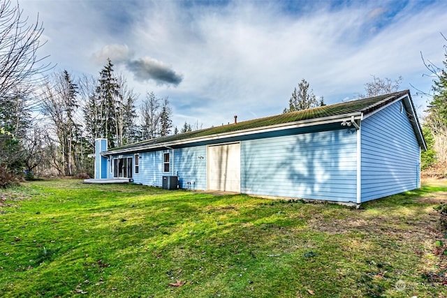 rear view of house featuring a lawn and central AC