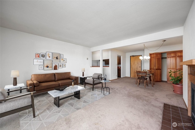 carpeted living room with a tile fireplace, a textured ceiling, and an inviting chandelier