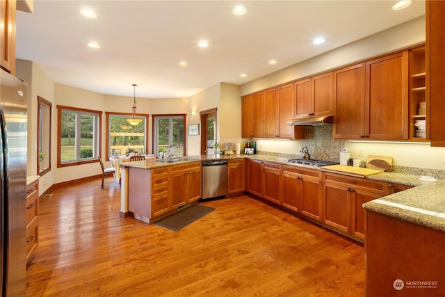 kitchen featuring appliances with stainless steel finishes, brown cabinets, under cabinet range hood, and a peninsula