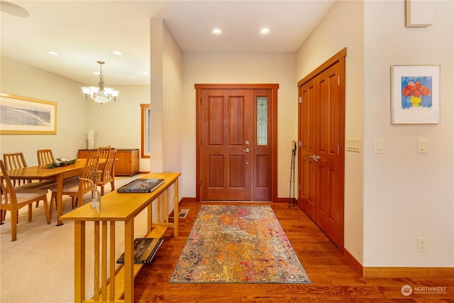 entryway with baseboards, a notable chandelier, wood finished floors, and recessed lighting