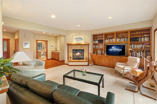 living area featuring light carpet, recessed lighting, and a glass covered fireplace