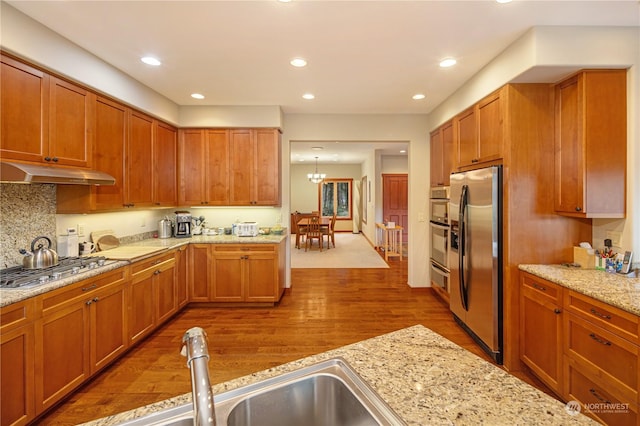 kitchen featuring recessed lighting, under cabinet range hood, stainless steel appliances, a sink, and wood finished floors