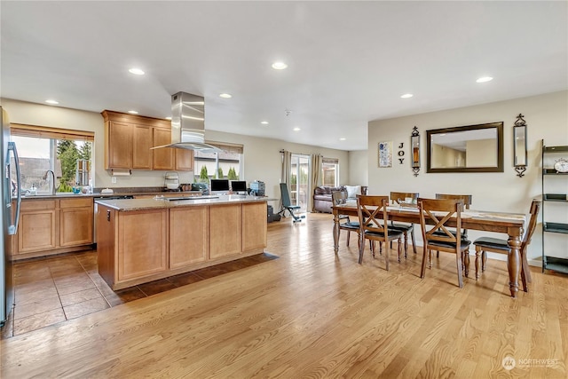 kitchen featuring a center island, light hardwood / wood-style floors, sink, island range hood, and light stone counters