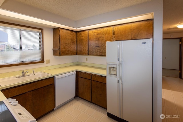 kitchen with a textured ceiling, sink, and white appliances