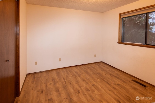 spare room with a textured ceiling and light wood-type flooring