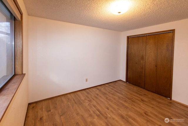 unfurnished bedroom with a closet, a textured ceiling, and light hardwood / wood-style flooring